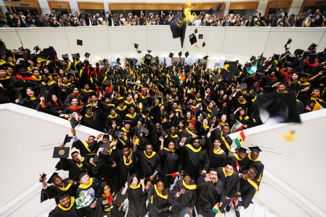 A shot from above of a crowd of graduates throwing their caps into the air.