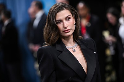 Hailey Bieber wearing a black blazer and silver necklace posing for a photo on the red carpet.