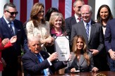 President Donald Trump holds up the signed Take It Down Act during a White House Rose Garden ceremony, joined by First Lady Melania Trump and supporting lawmakers.