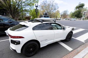 A white self-driving SUV style car on a street in Washington D.C.