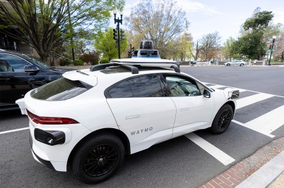 A white self-driving SUV style car on a street in Washington D.C.