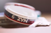 A circular canister that says &#039;ZYN&#039; on it in all caps.