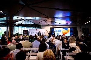 Audience members sitting at tables photographed from behind at the AI in Action Business Summit.