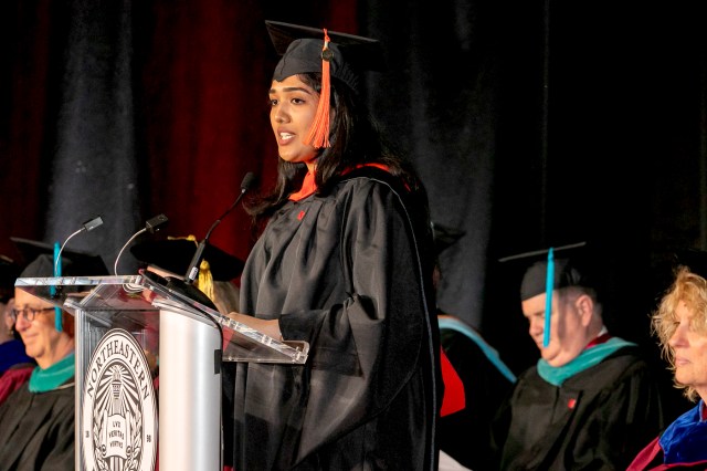 A graduate speaks at a podium during a commencement ceremony.