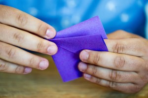 A close-up of a person holding a piece of purple origami.
