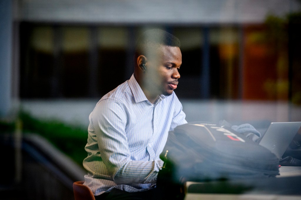A person focuses on their work while seated indoors with a laptop.