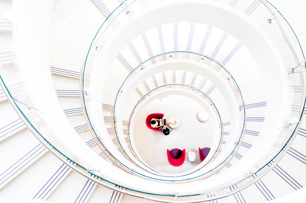 A person sits at the center of a circular architectural space viewed from above.
