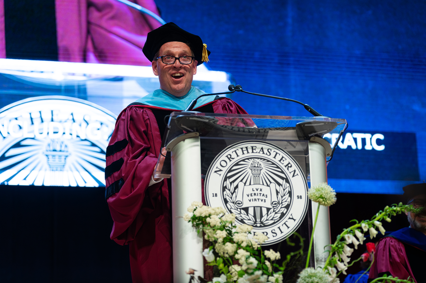 A speaker in academic regalia addresses the audience during the Northeastern commencement in Portland.