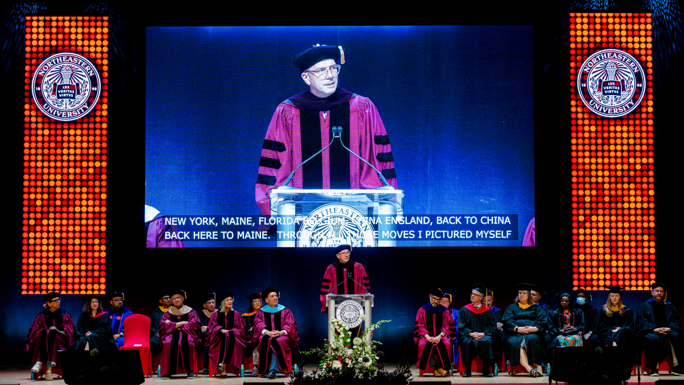 A large screen shows a speaker onstage during a ceremony..