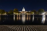 Night view of the US Capitol with lights reflecting on the water.