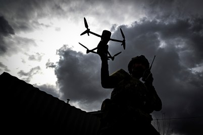 The silhouette of a person and a drone is shown against the backdrop of dark clouds.