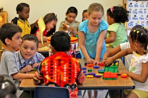 Children play and collaborate with colorful interlocking blocks at a classroom table in an early childhood education center.