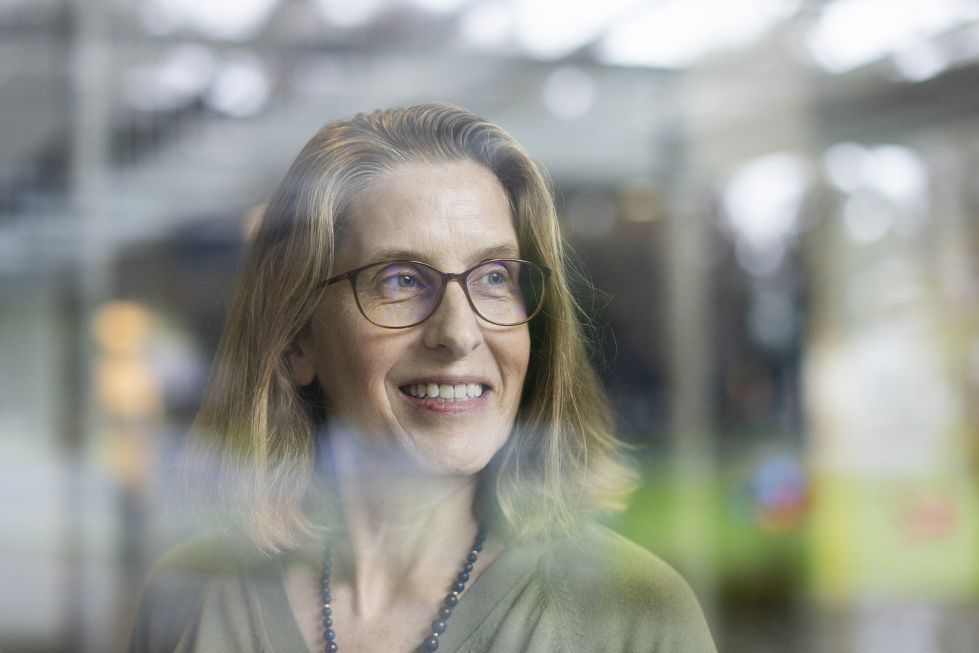 Jessica Staddon posing for a portrait through a window. 