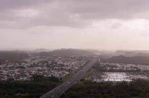 Clouds and dust partially obscure the view of a highway and city in Puerto Rico.