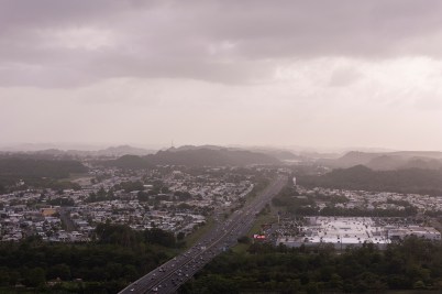 Clouds and dust partially obscure the view of a highway and city in Puerto Rico.