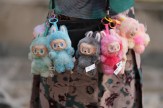 A close-up of seven colorful Labubu plush charms clipped to a crossbody bag.