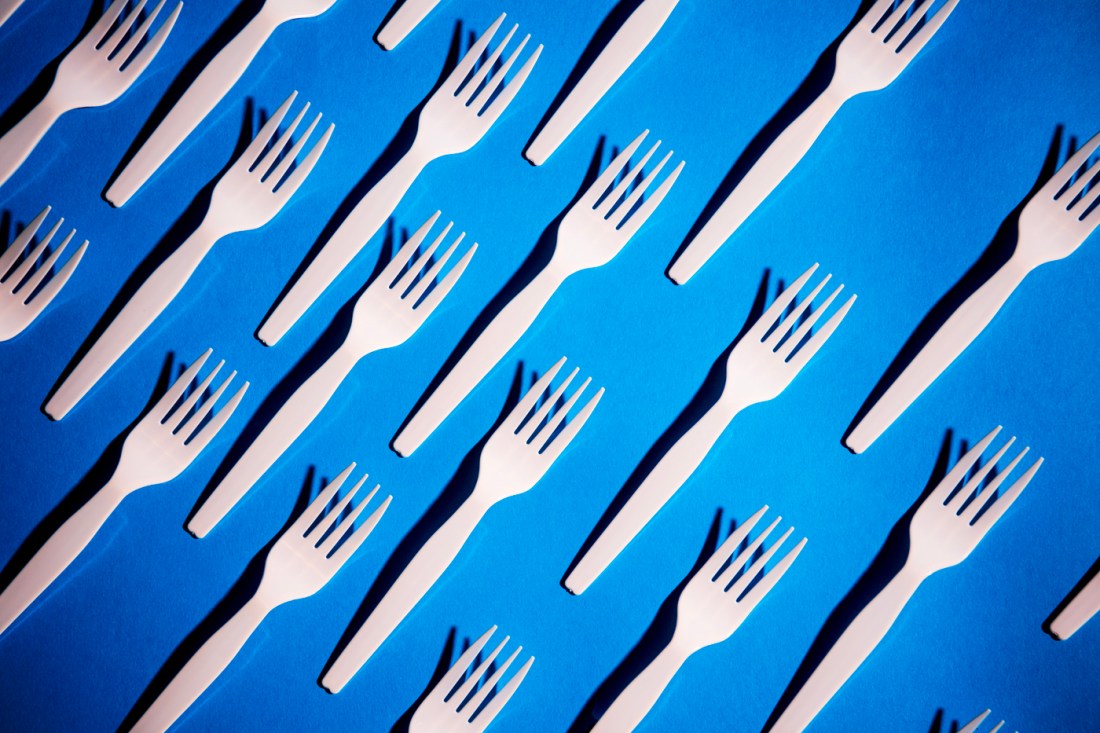 Rows of plastic forks against a blue background.