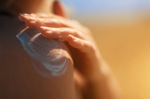 A woman's hand rubbing a layer of sunscreen into her shoulder.