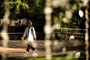 A person walks through an outdoor campus space on a sunny day.