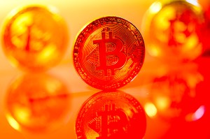 A bitcoin shown against a reddish orange glare.