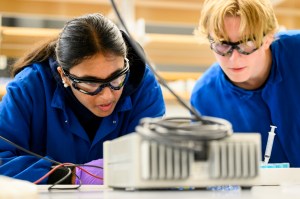Two students wearing goggles looking at a model.