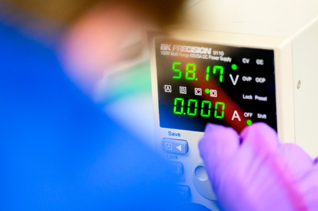 A student wearing gloves watching a monitor.