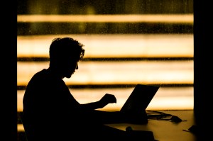 A person works on a laptop in a dimly lit space.