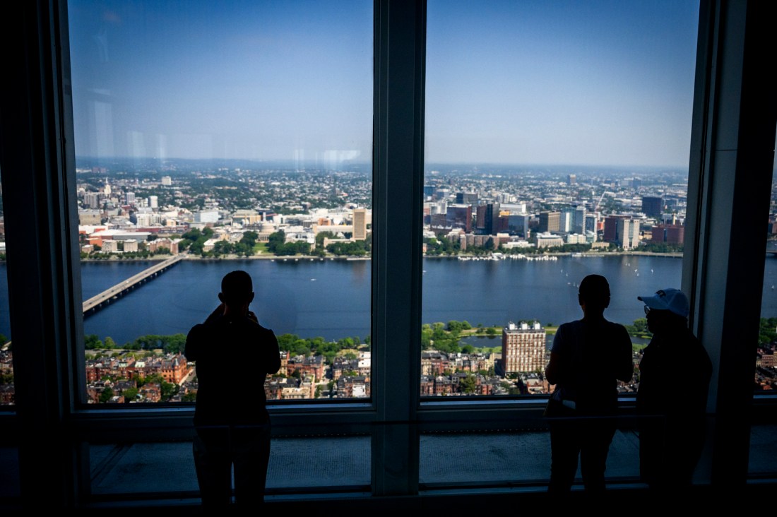 The silhouette of three people overlooking the Charles River from the Prudential Center.