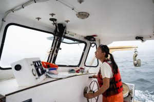 Northeastern student Miranda Shinn shown steering a boat wearing a life jacket.