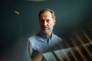 Lorenzo Torresani shown in a blue shirt looking past the camera agaisnt a blue-grey background.