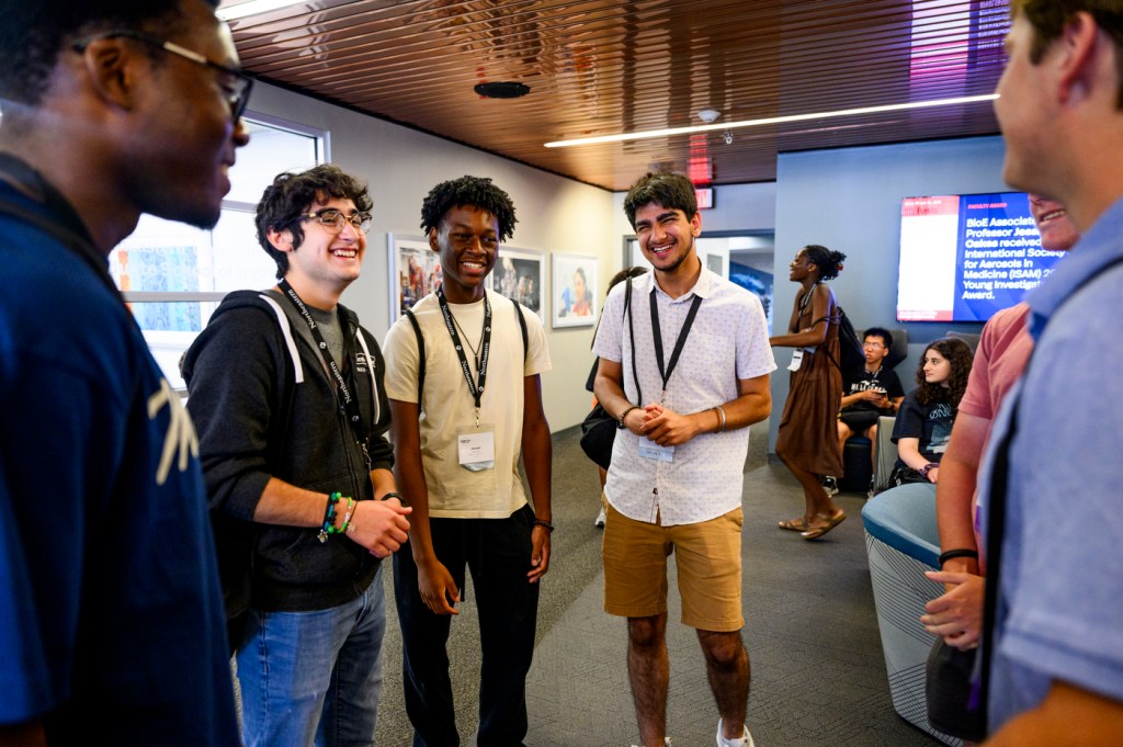 A group of people stand in conversation inside a brightly lit building.