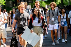 A group of Northeastern students walk together on campus during orientation, smiling and enjoying the sunny day.