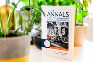 A close-up of the book, The ANNALS of the american academy of political and social science, propped up against a plant.