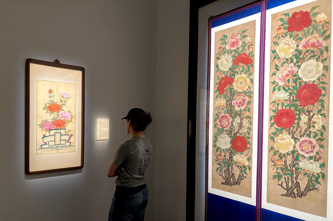 A person standing with their back to the camera facing a piece of art on the wall of a museum or other gallery space.