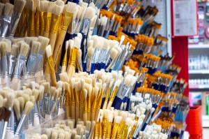 Groups of paintbrushes in a row on a wall for sale.