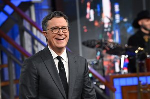 A screen capture of Stephen Colbert in a suit laughing on the set of 'The Late Show'.