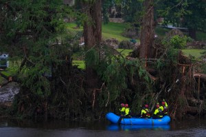 A group of rescue workers wearing neon jackets in a blue boat searching for missing people in a flooded area of Texas.