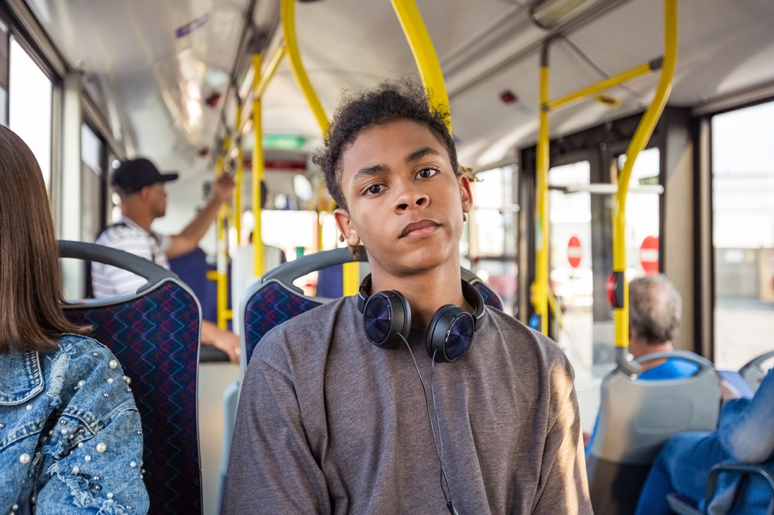 A young person on a bus staring blankly at the camera.