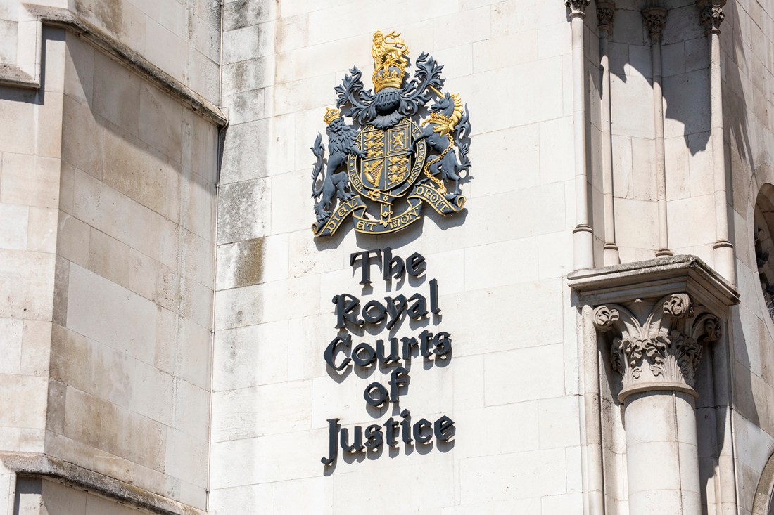 The exterior of a court building with a royal court of arms and 'The Royal Courts of Justice' on it.