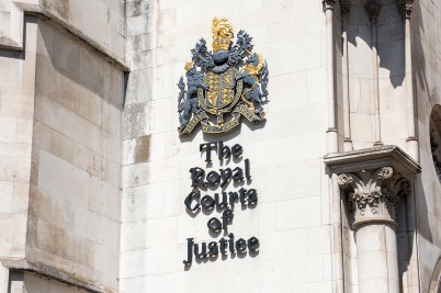 The exterior of a court building with a royal court of arms and 'The Royal Courts of Justice' on it.