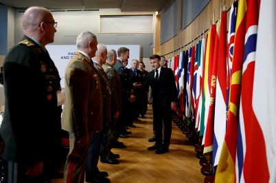European leaders lined up in front a series of flags to greet French President Emmanuel Macron.