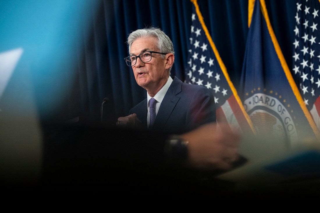Jerome Powell speaking at a podium to the media.