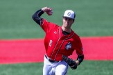 Cam Schlitter wearing a red and white Northeastern baseball uniform throwing a pitch on the baseball field.