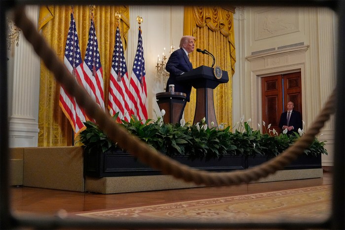 President Donald Trump appearing at a podium in front of several American flags.