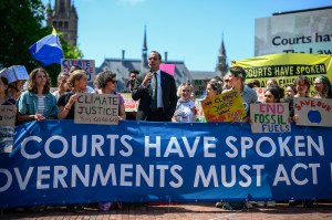 A group of climate protestors holding a blue sign urging governments to act.