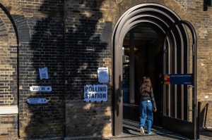 A woman entering a polling station through a large arched doorway in the UK.