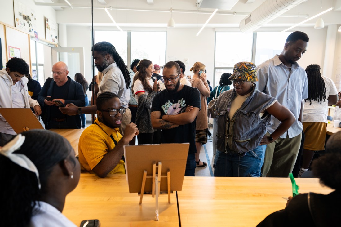 A group of people review a display that students made. Only the back of the display, on a small easel, is visible.