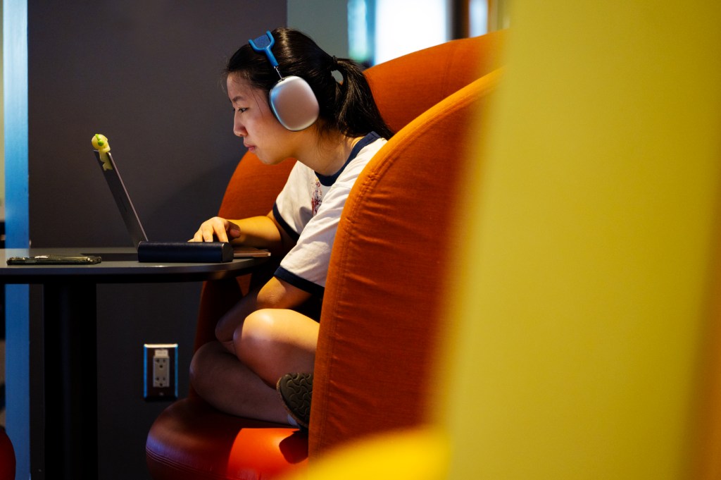 Student wearing headphones focuses intently on her laptop in a study booth