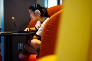Student wearing headphones focuses intently on her laptop in a study booth