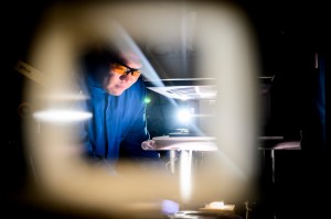 Yi Zheng, shown in a blue lab coat and goggles, at work in a Northeastern lab.